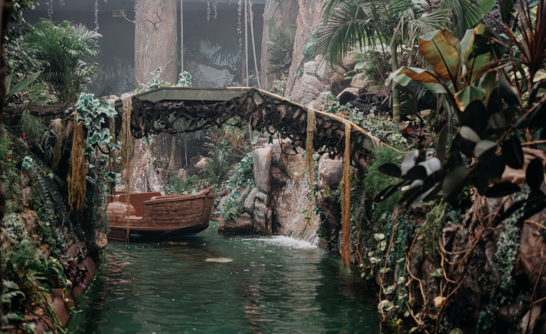 Barco en un entorno tropical con puente y vegetación densa en un espacio expositivo